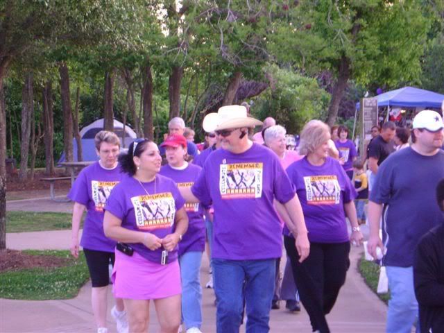 John, donning a cowboy hat, walks in the Relay for Life. Cancer survivors wear purple shirts.